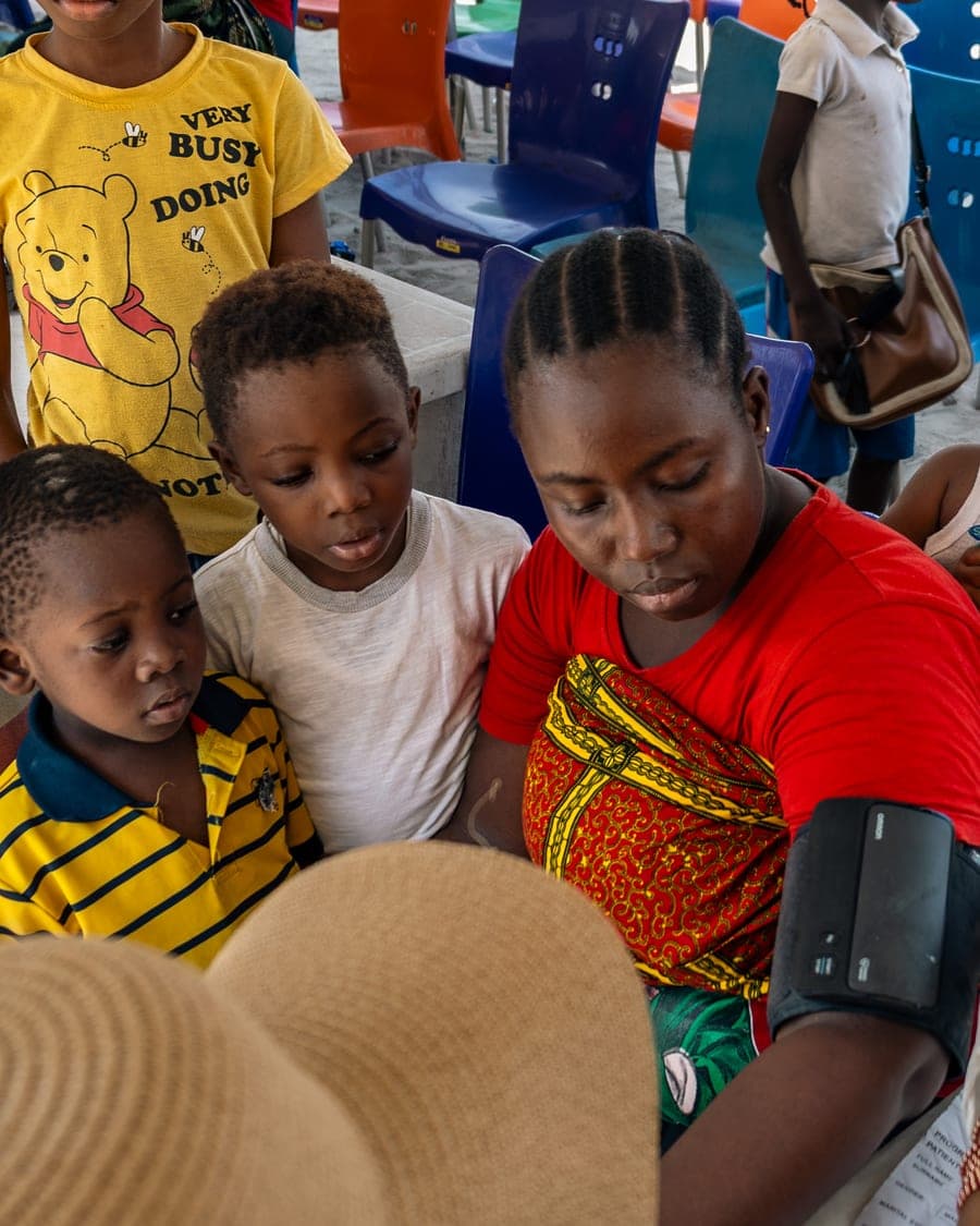 A woman has her blood pressure taken with her children beside her at the Ilasan medical outreach in Lekki, Lagos.