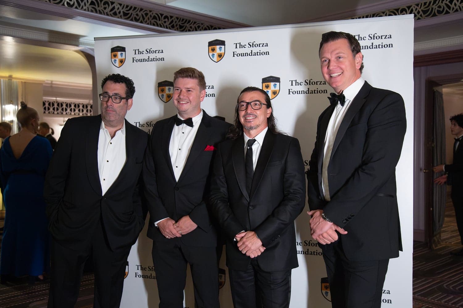 Four guests in black tie at the Sforza Foundation's Inaugural Gala Ball, photographed against the Foundation's backdrop.