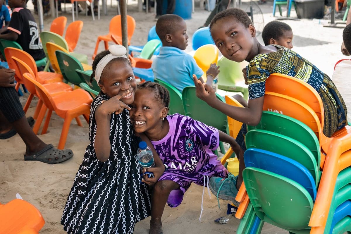 Children looking out from behind stacks of brightly coloured chairs at the outreach.