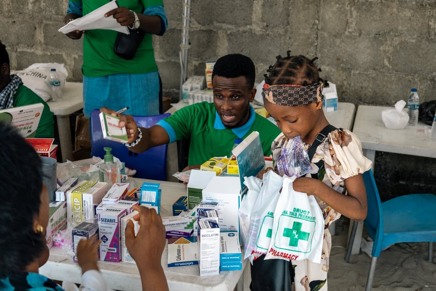 A girl receiving a bag of medicine at the pharmacy table.