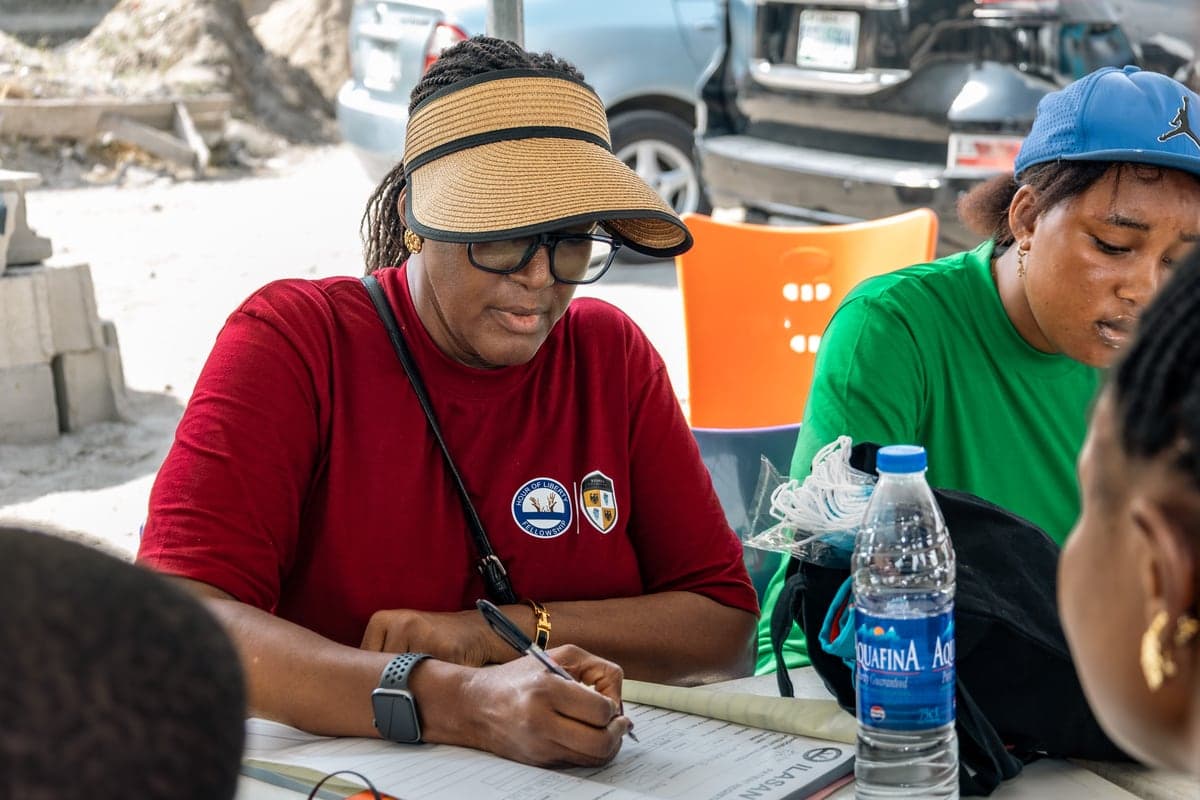 A volunteer writing in a paper ledger at the registration table.