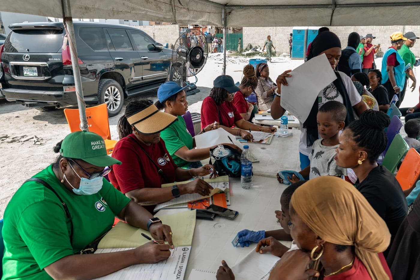 Volunteers at long tables completing registration forms with a queue of people waiting.