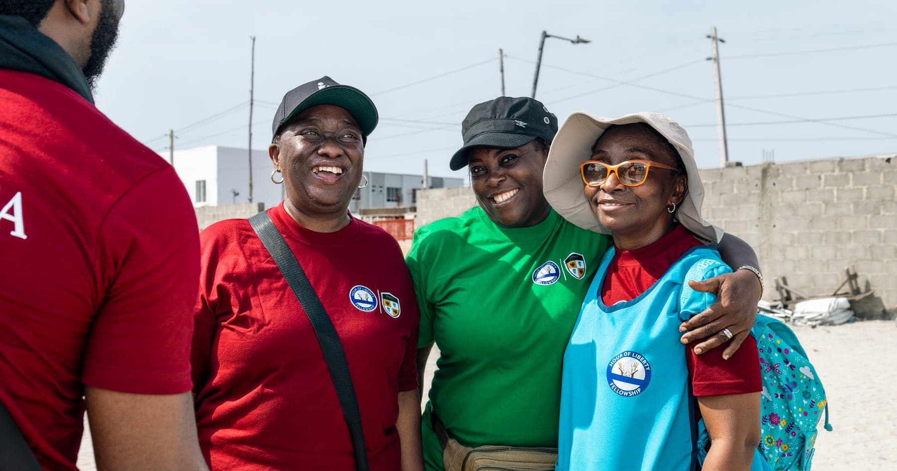 Four volunteers in branded shirts standing together outdoors at the outreach.