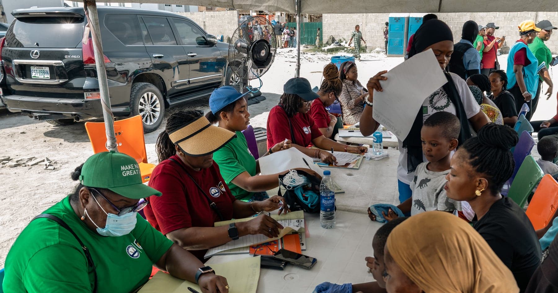 Volunteers completing registration paperwork at long tables under the marquee.