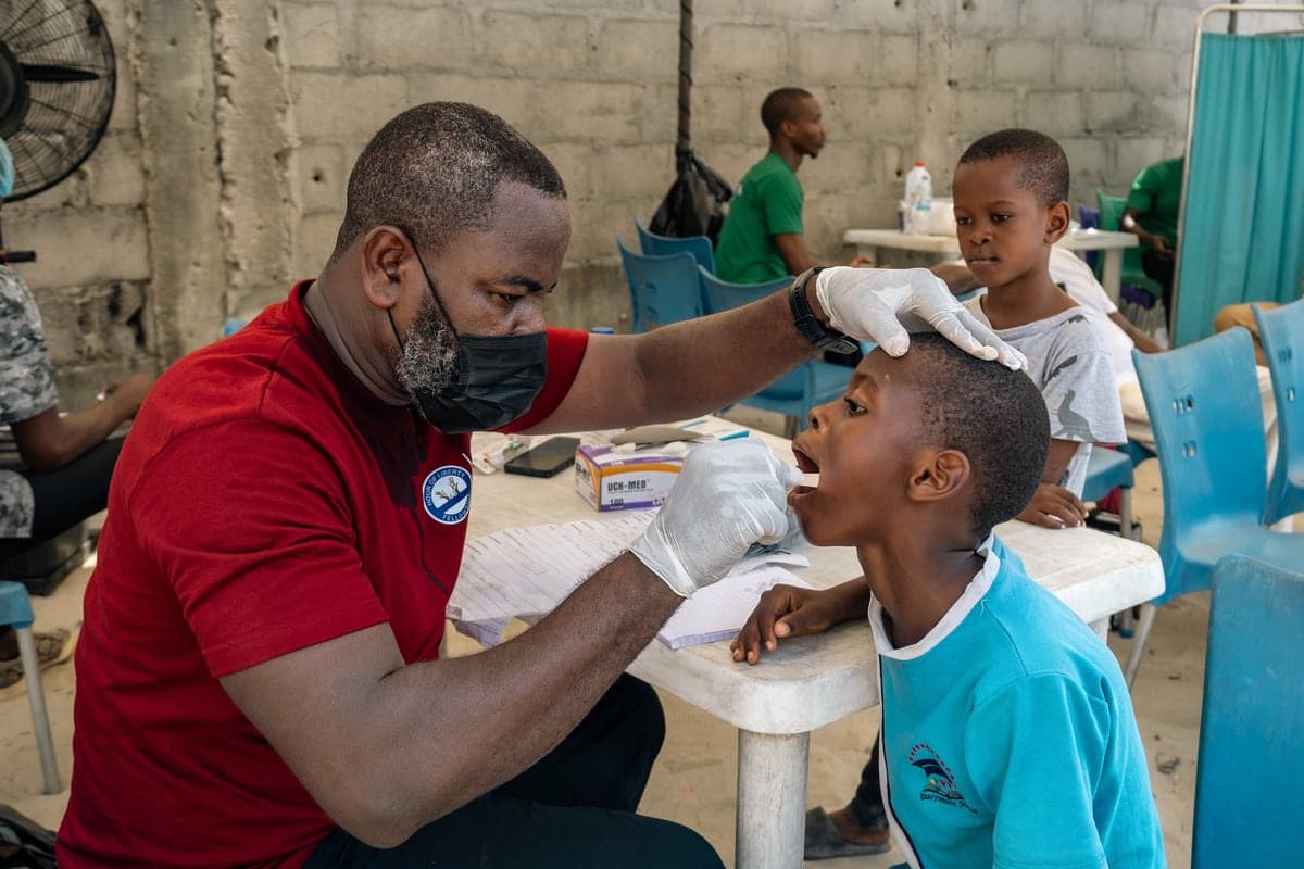 A clinician examining a boy's teeth at the dental station.
