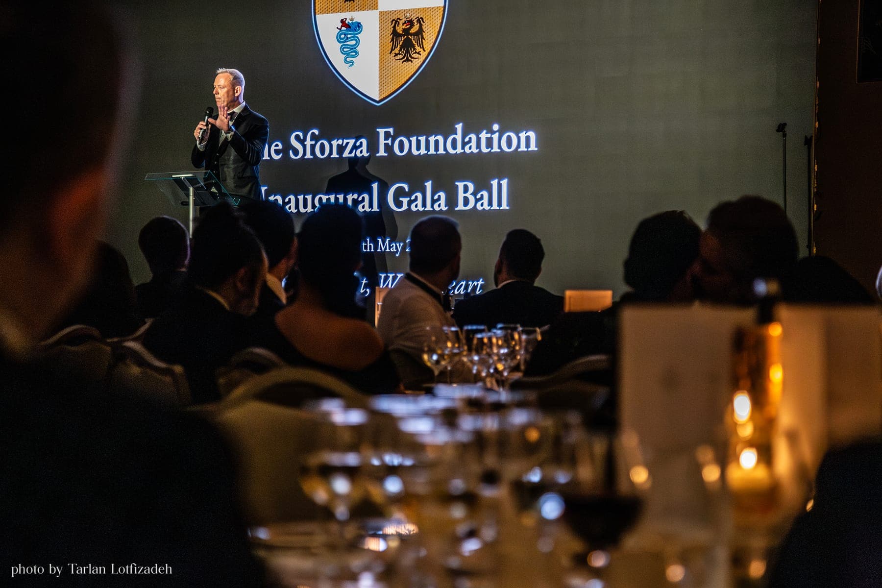 A speaker at the podium beneath the Foundation's crest at the 2025 Inaugural Gala Ball.